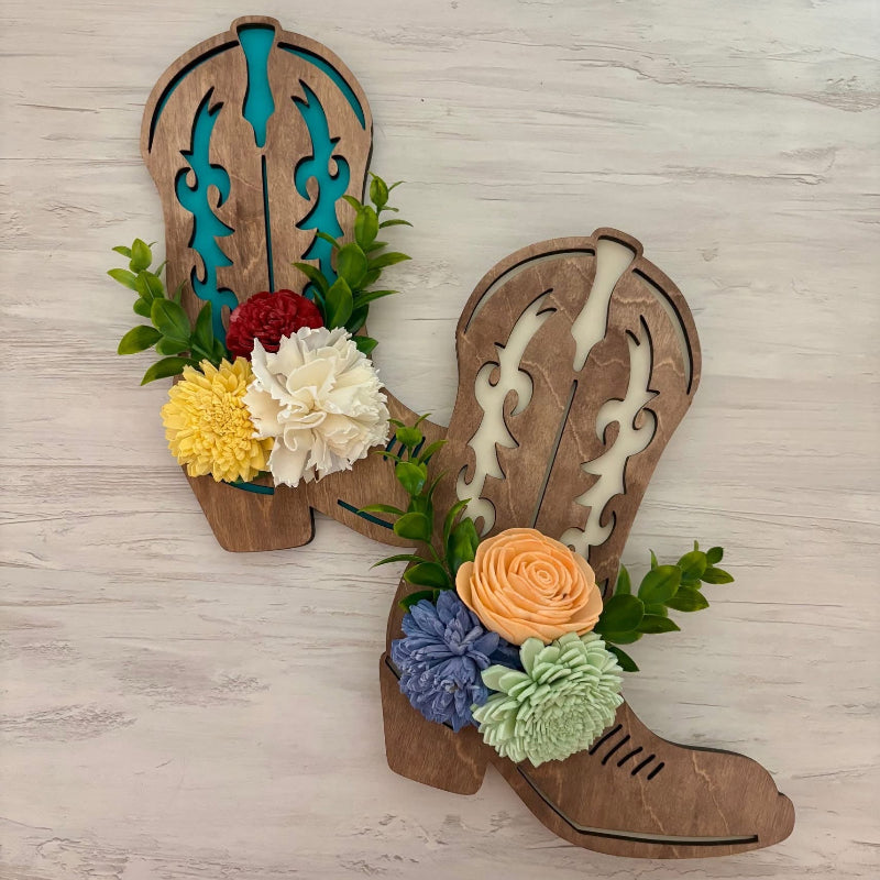Pair of wooden cowboy boots decorated with wood dyed flowers and greenery.