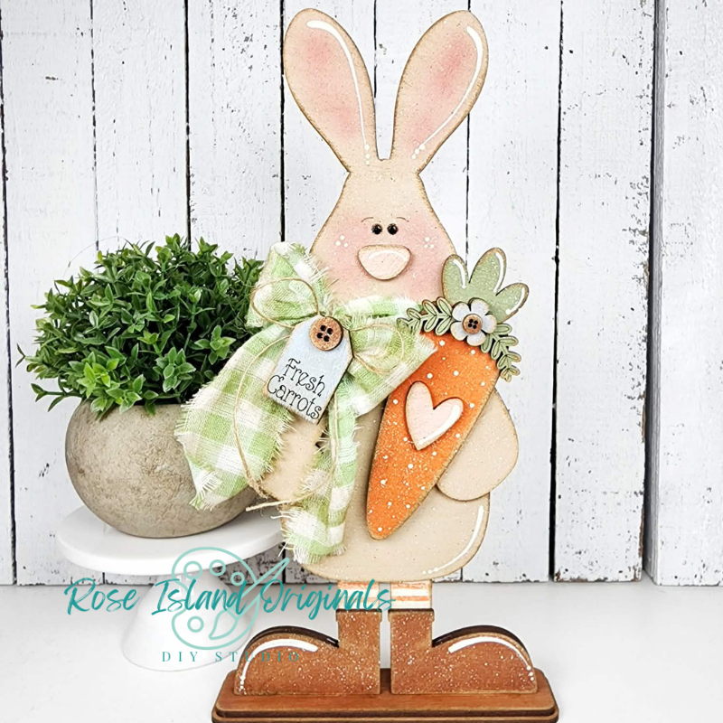 Decorative bunny with a carrot and a plant on a white background