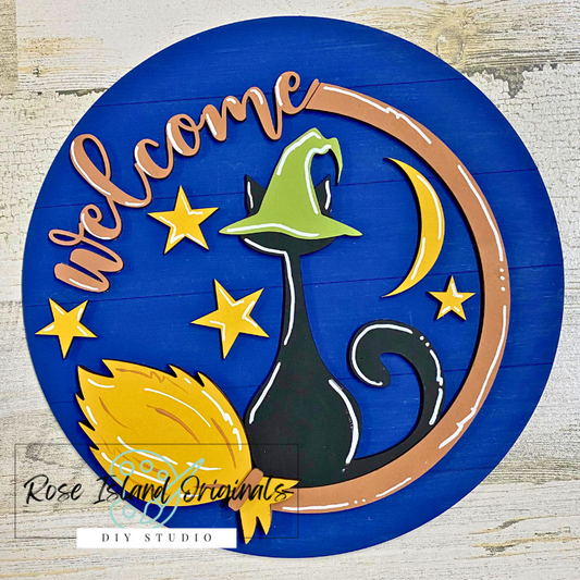 Decorative Welcome sign with a cat, moon, and stars on a blue background.