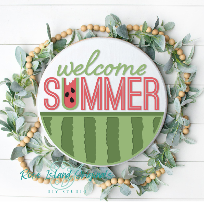 Round wooden wall sign reading 'welcome SUMMER' with a watermelon-themed design, surrounded by a green eucalyptus wreath with tan beads on a white shiplap background. A watermark at the bottom reads Rose Island Creations DIY Studio.