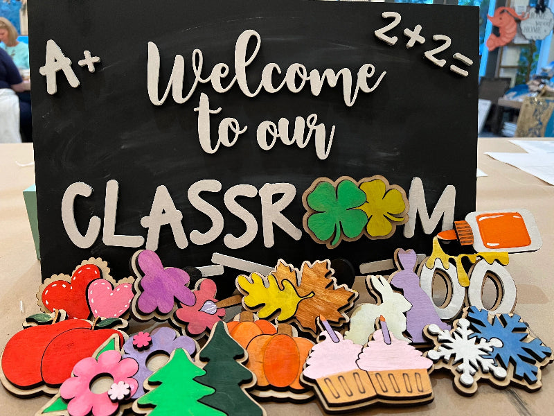 Decorative classroom sign with colorful interchangeable cutout seasonal shapes.