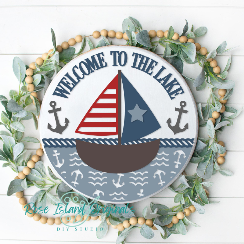 Round wooden sign with a sailboat and anchors with words welcome to the lake