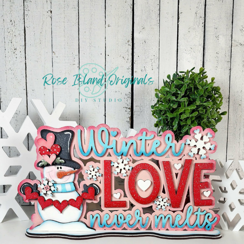 Decorative sign with snowman and text 'Winter Love never melts' on a wooden background.