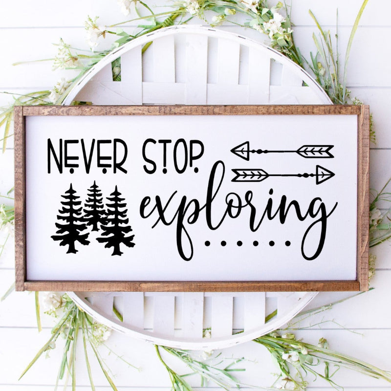 Decorative sign with 'Never stop exploring' text on a white background with greenery.