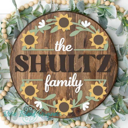 Round sign with words the shultz family border of sunflowers on a wood background.