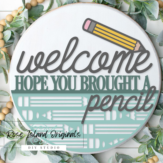 Round Welcome sign featuring a pencil design with words welcome hope you brought a pencil on a white background