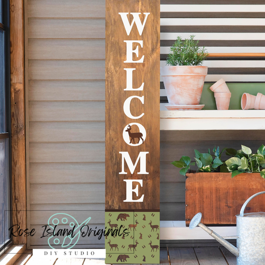 Wooden 'Welcome' sign with a vertical design on a porch with plants and a watering can.